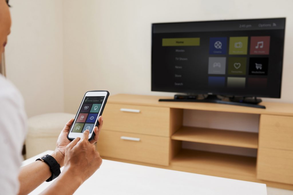 Woman connecting her smartphone to her smart TV