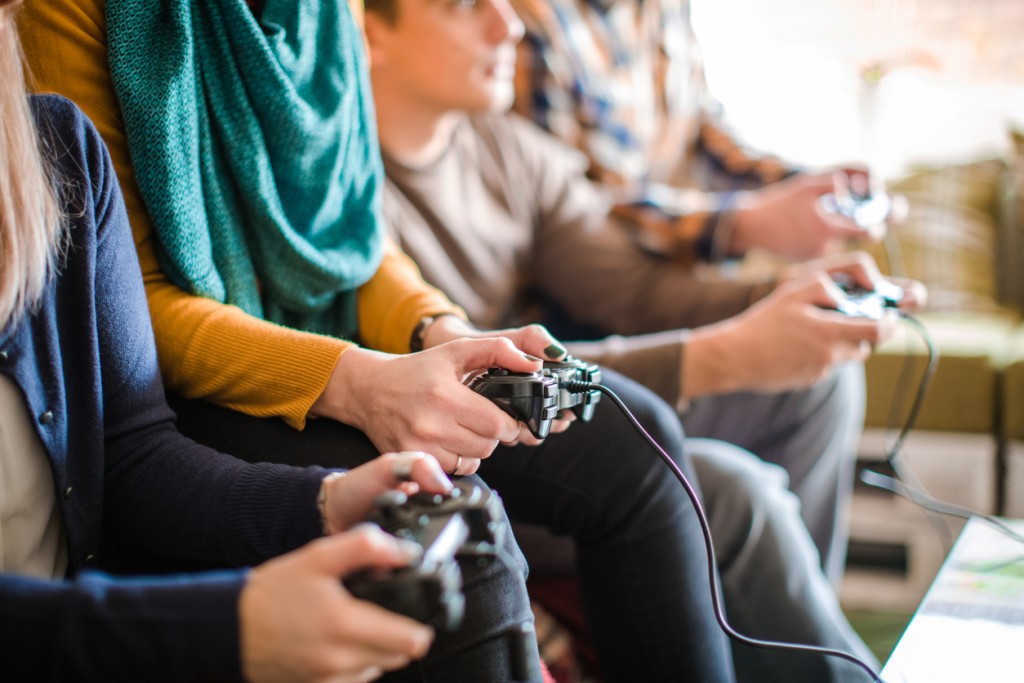 Group of young happy friends playing video games at home.