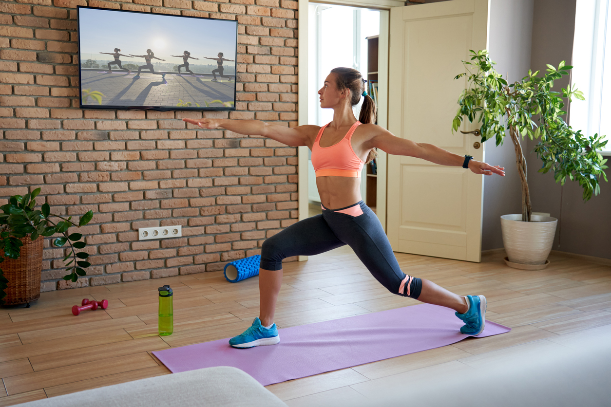 Fit woman learning yoga pose watching streaming online workout on tv at home.